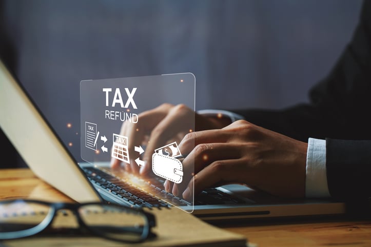 Businessman hand using a laptop with bar TAX REFUND and refund tax of duty taxation business, tax form, and wallet money being demonstrated on the screen media, online for tax payment.tax returns