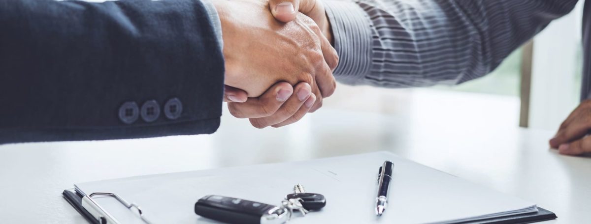 Sales person and customer shaking hands after reaching an agreed upon sale price of a new or used car