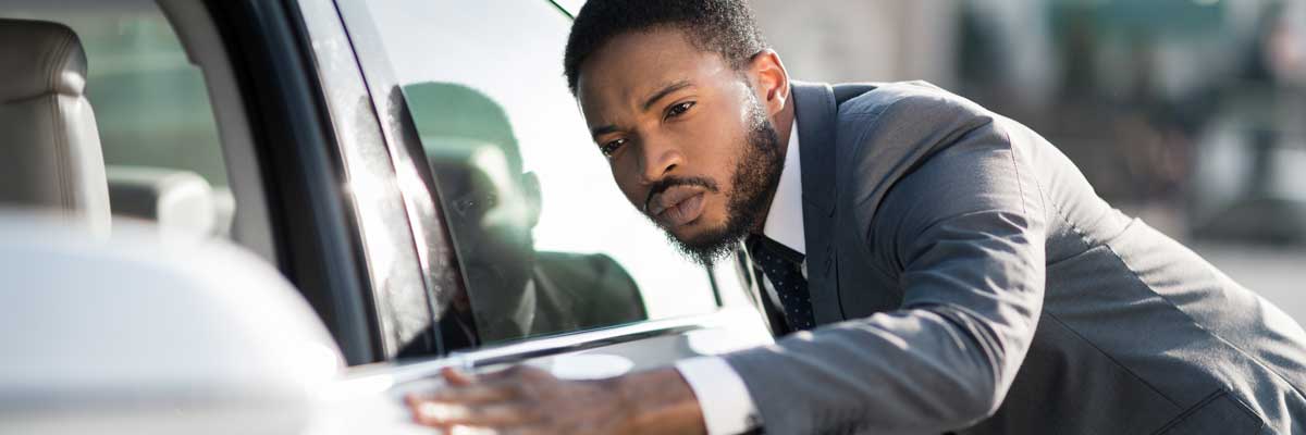 Man inspecting new or used car looking for any imperfections before sale