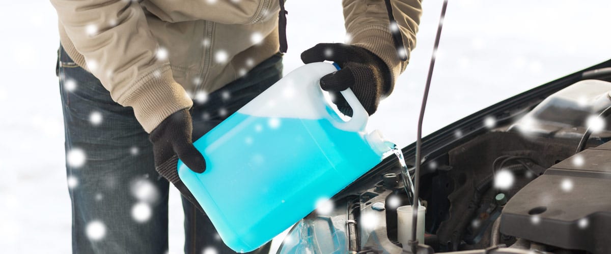 transportation, winter, people and vehicle concept - closeup of man pouring antifreeze into car