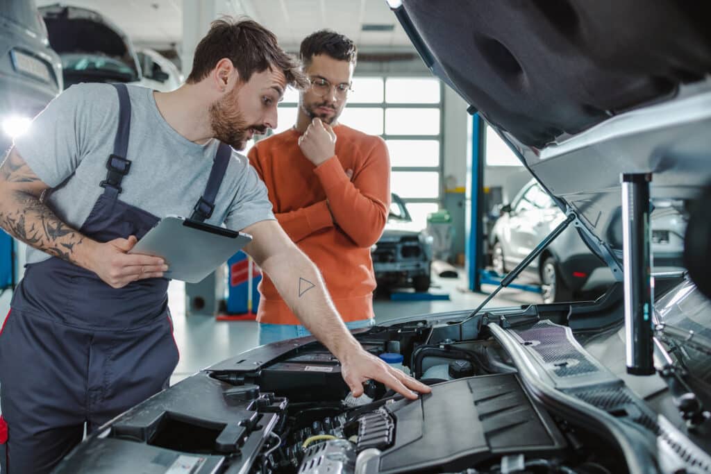 Auto mechanic explaining the problem to the customer while using digital tablet in a repair shop