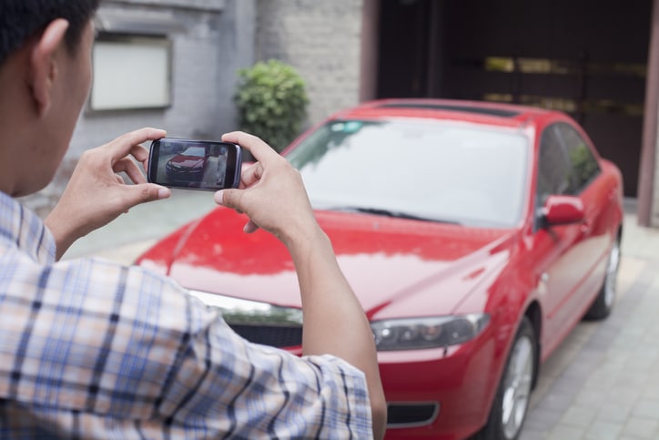 Man taking a photo of his red car